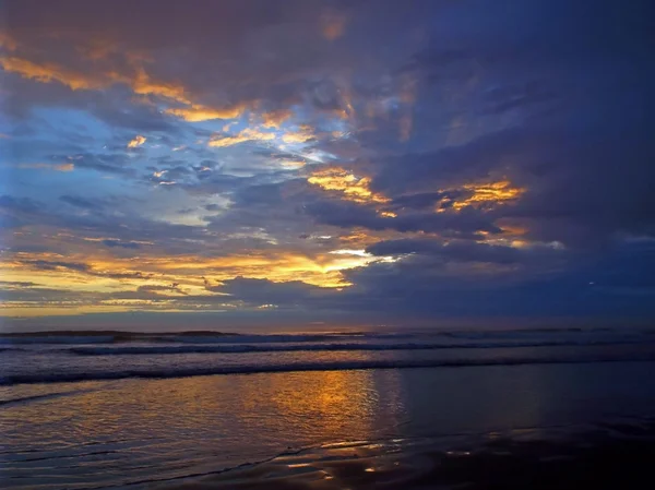 Pôr-do-sol nublado sobre o oceano com ondas em primeiro plano — Fotografia de Stock