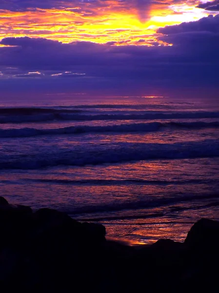 Bewolkt zonsondergang Over de oceaan met golven op de voorgrond — Stockfoto