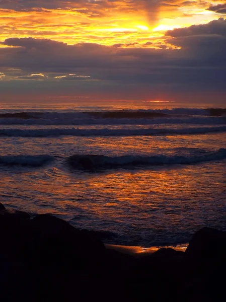 Pôr-do-sol nublado sobre o oceano com ondas em primeiro plano — Fotografia de Stock