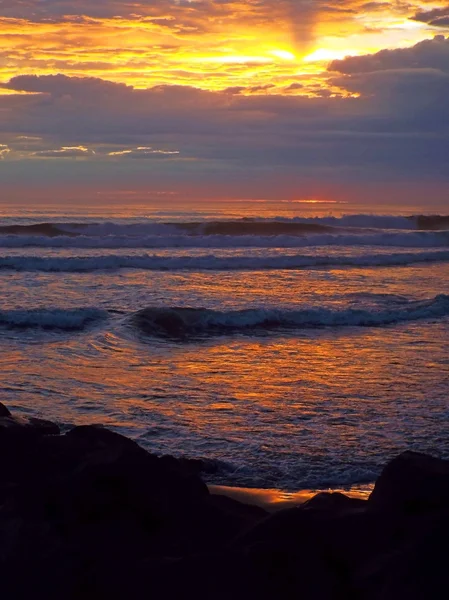 Tramonto nuvoloso sull'oceano con onde in primo piano — Foto Stock