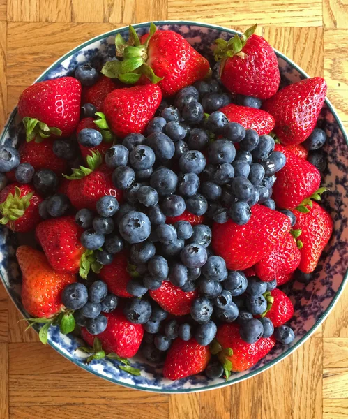 Erdbeeren und Blaubeeren in einer Schüssel auf einem Holztisch lizenzfreie Stockbilder