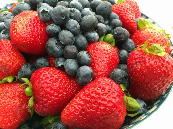 Erdbeeren und Blaubeeren in einer Schüssel auf einem Holztisch lizenzfreie Stockfotos