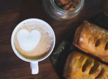 Latte kalpli bir fincan kahve. Kahve ve çöreklerle nefis ve yaratıcı bir kahvaltı..