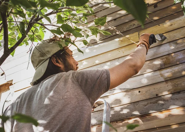 Hombre pintando pared de madera de la casa al aire libre — Foto de Stock