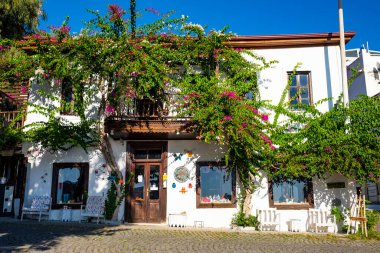 Kalkan, Türkiye - 4 Kasım 2020: Yakındaki bougainvillea ağaçlarıyla beyaz ve ahşap eski bina
