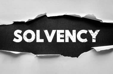 Yırtık kağıt konseptiyle gösterilen SOLVENCY kelimesi. Şirket varlıklarını, borç yönetimini, mali sorumluluğu ve sürdürülebilir ekonomik yapıyı temsil eden mali istikrar sembolü