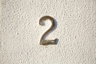 Metalik numara 2, beyaz bir duvar üzerine monte edilmiş. Temiz yansıtıcı yüzey ve mimari basitliğe sahip minimalist şehir tasarımı
