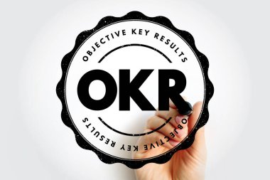 OKR metni yuvarlak bir pul tasarımı ile sınırda yazılmış Hedef Anahtar Sonuçları ve çerçeve içinde bir işaret tutan bir el, hedef belirleme odaklı temiz bir şirket rozet konsepti oluşturur