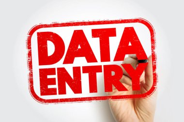 Bir el tarafından tutulan DATA Giriş damgası, çerçeveli bir rozet içindeki kalın blok harfleri, basit bir nötr arkaplan üzerindeki idari çalışmaları, dijital girdi görevlerini ve ofis operasyonlarını sembolize ediyor