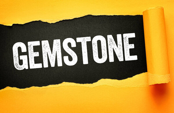 Gemstone text revealed on torn paper background, conceptual image symbolizing minerals, jewelry materials, natural value, geology interest, collecting passion, and luxury resource significance