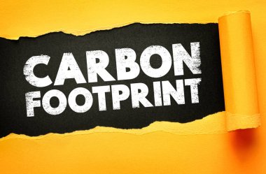 Yırtık kağıt zemin üzerinde sunulan karbon ayak izi metni çevresel etki ölçümünü, emisyon sorumluluğunu, sürdürülebilirlik bilincini, kaynak tüketimini ve ekolojik denge çabalarını sembolize etmektedir