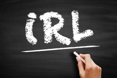 Tahtada IRL metni var. Gerçek hayatta gerçekliği dijital uzaydan ayırmak için kullanılan genel bir kısaltma. Tahtaya tebeşirle el yazısı.