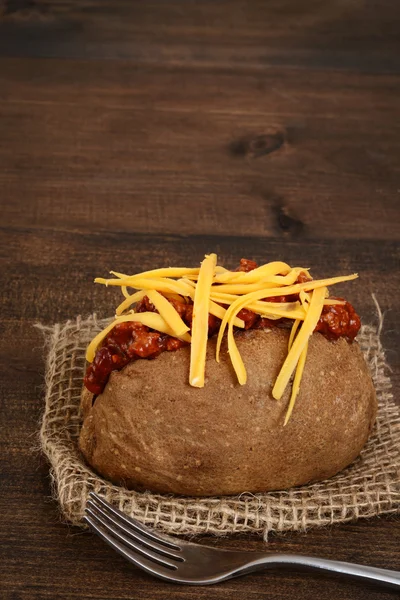 Baked potato with chili cheese and a fork — Stock Photo, Image