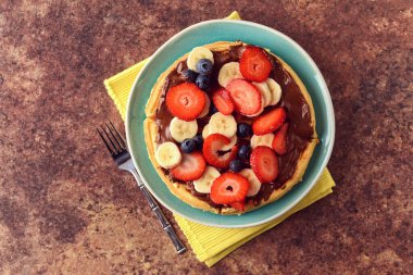 Yüksek açılı meyveli waffle, çikolata kaplı ve çatallı.