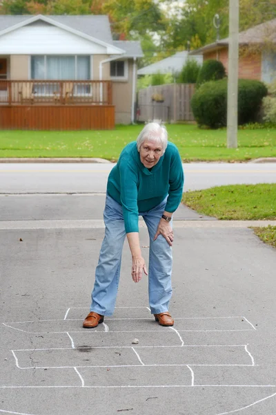 Senior vrouw spelen Hinkelspel — Stockfoto