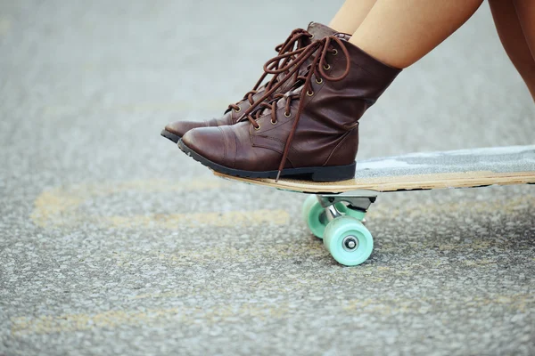 Primer plano chica con botas sentado en skate board —  Fotos de Stock