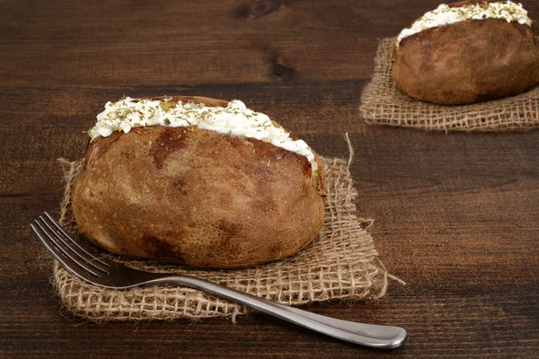 Baked potato with sour cream and a fork — Stock Photo, Image