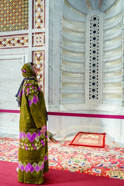 オマーンのマスカットにあるムハンマド アミン モスクで華やかな床の間を見る伝統的なオマーニアバヤを着た女性 — ストック写真