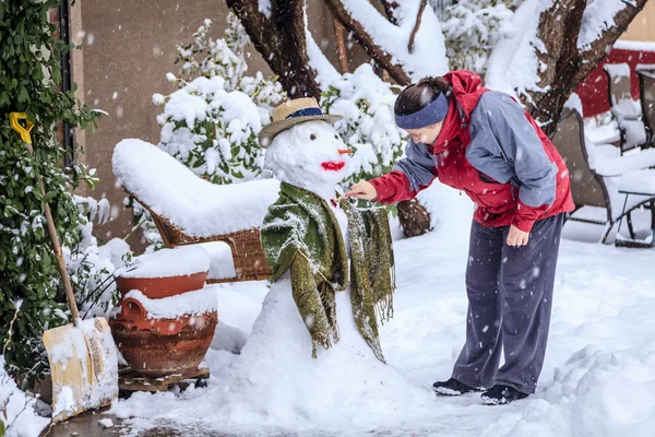 Vrouw maakt sneeuwpop — Stockfoto