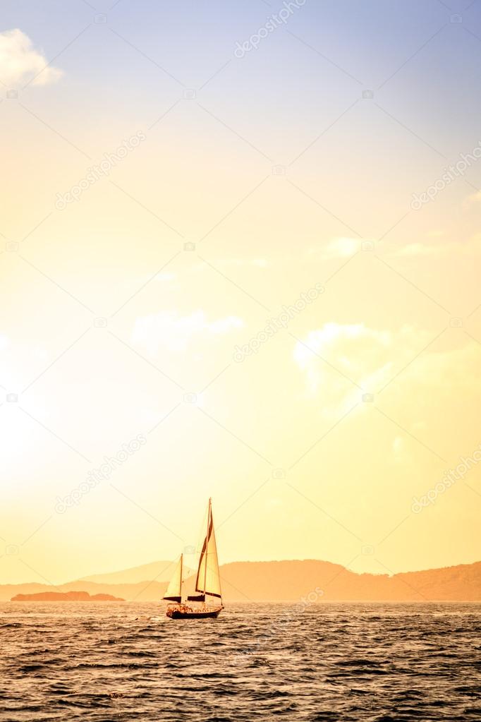 Sailboat under sails at sunset