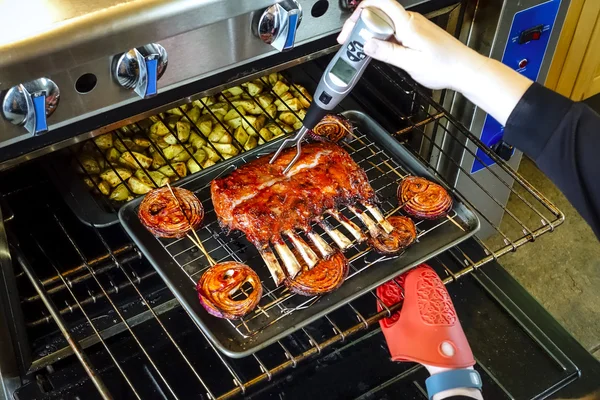 Person checking temperature of rack of lamb — Stock Photo, Image