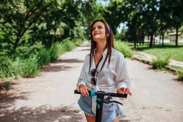 Cute Brunetka Dziewczyna Jeździ Skuterze Elektrody Parku Sobie Białą Koszulę — Zdjęcie stockowe