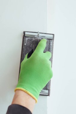 Yeşil eldivenli bir adam duvara sürtünüyor.