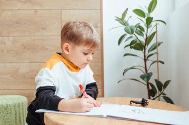 a blond boy is playing with a construction kit, with a wooden wall in the background.
