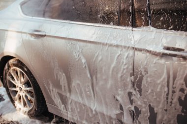 a man washes a car with a pistol at a self-service car wash