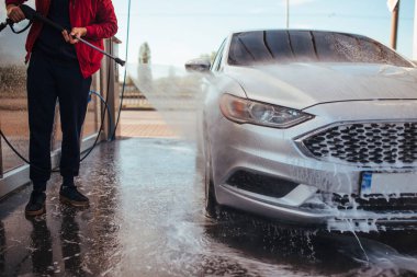 a man washes a car with a pistol at a self-service car wash