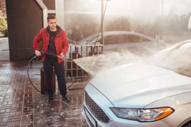 a man washes a car with a pistol at a self-service car wash
