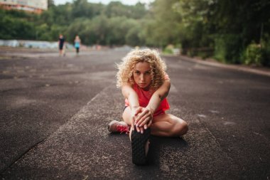 Kız sporcu antrenmandan önce esneme hareketleri yapıyor.