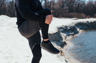 Sporcu doğada antrenman yapmadan önce bacaklarını açıyor.