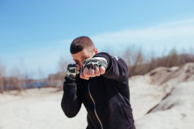 Pompalı bir boksör kumda trenlere biner, ön planda yumruklar