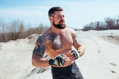 Kaslı boksör çıplak bir gövdeyle kumda çalışır.