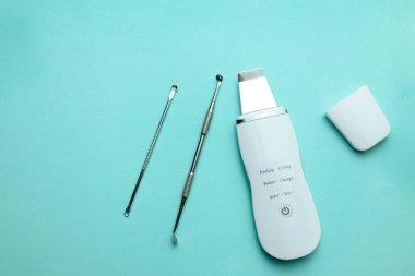 Ultrasonik temizleyici, tek kaşık yumuşak mavi arka planda yatıyor. düz alan, kozmetoloji ve araçlar konsepti