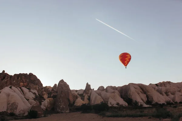 hovering hot air balloon over the mountains of cappadocia