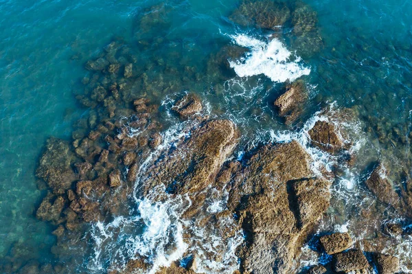 Vista aerea. Le onde del Mar Mediterraneo della Turchia battono sulle rocce. Il surf di acqua di mare turchese è girato in altezze — Foto Stock