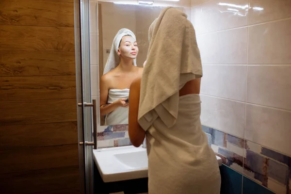 Spa e cosmetologia. Cura della pelle del viso a casa. Ragazza in bagno applica una maschera crema viso — Foto Stock