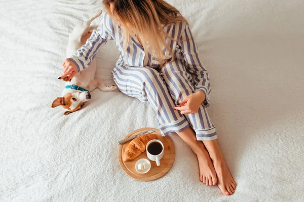 Morning breakfast in bed croissant and coffee. next to her is a woman in pyjamas — Stock Photo, Image