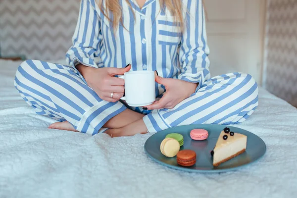 Una mujer por la mañana bebe café y come dulces tarta de queso macarrones dulces —  Fotos de Stock