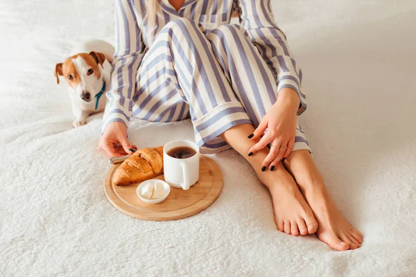 Desayuno por la mañana en la cama croissant y café. junto a ella hay una mujer en pijama —  Fotos de Stock
