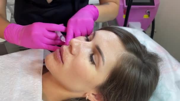 Cosmetoloog arts is het maken van meerdere injecties biorevitalisatie met hyaluronzuur in de huid van de vrouw gezicht, close-up. Vrouw op de procedure van mesotherapie injectie — Stockvideo