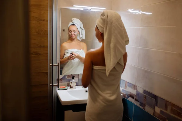 温泉和化妆品学 面部皮肤护理在家里 浴室里的女孩用奶油面罩 — 图库照片