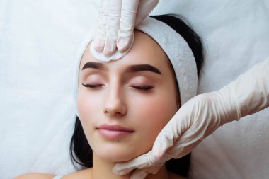 Cilde iyi gelir. Bir kadının yüzünde kozmetik krem. Spa güzellik tedavileri. Yüz bakımı. Yüksek kalite fotoğraf