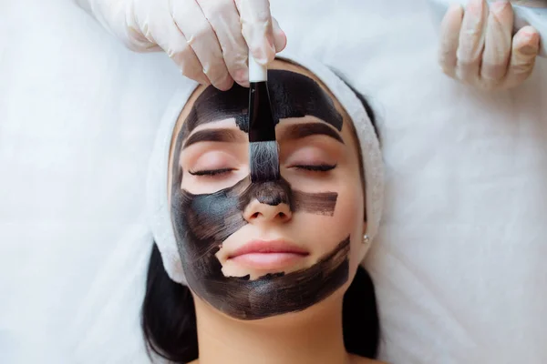 Cosmetoloog Toepassen Van Zwart Masker Mooie Vrouw Gezicht Dragen Van — Stockfoto