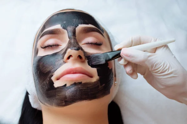 Kosmetolog Stosujący Czarną Maskę Ładnej Kobiecej Twarzy Czarnych Rękawiczkach Piękna — Zdjęcie stockowe