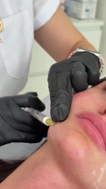 Estetik tıp: Siyah eldivenli kozmetik uzmanı tarafından kadınlara kanül enjeksiyonuyla kolajen biyo-evrizasyon tedavisine yakın çekim.