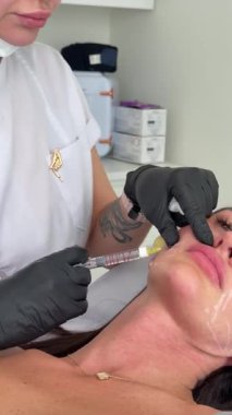 Estetik tıp: Siyah eldivenli kozmetik uzmanı tarafından kadınlara kanül enjeksiyonuyla kolajen biyo-evrizasyon tedavisine yakın çekim.