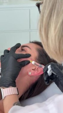 Estetik tıp: Siyah eldivenli kozmetik uzmanı tarafından kadınlara kanül enjeksiyonuyla kolajen biyo-evrizasyon tedavisine yakın çekim.